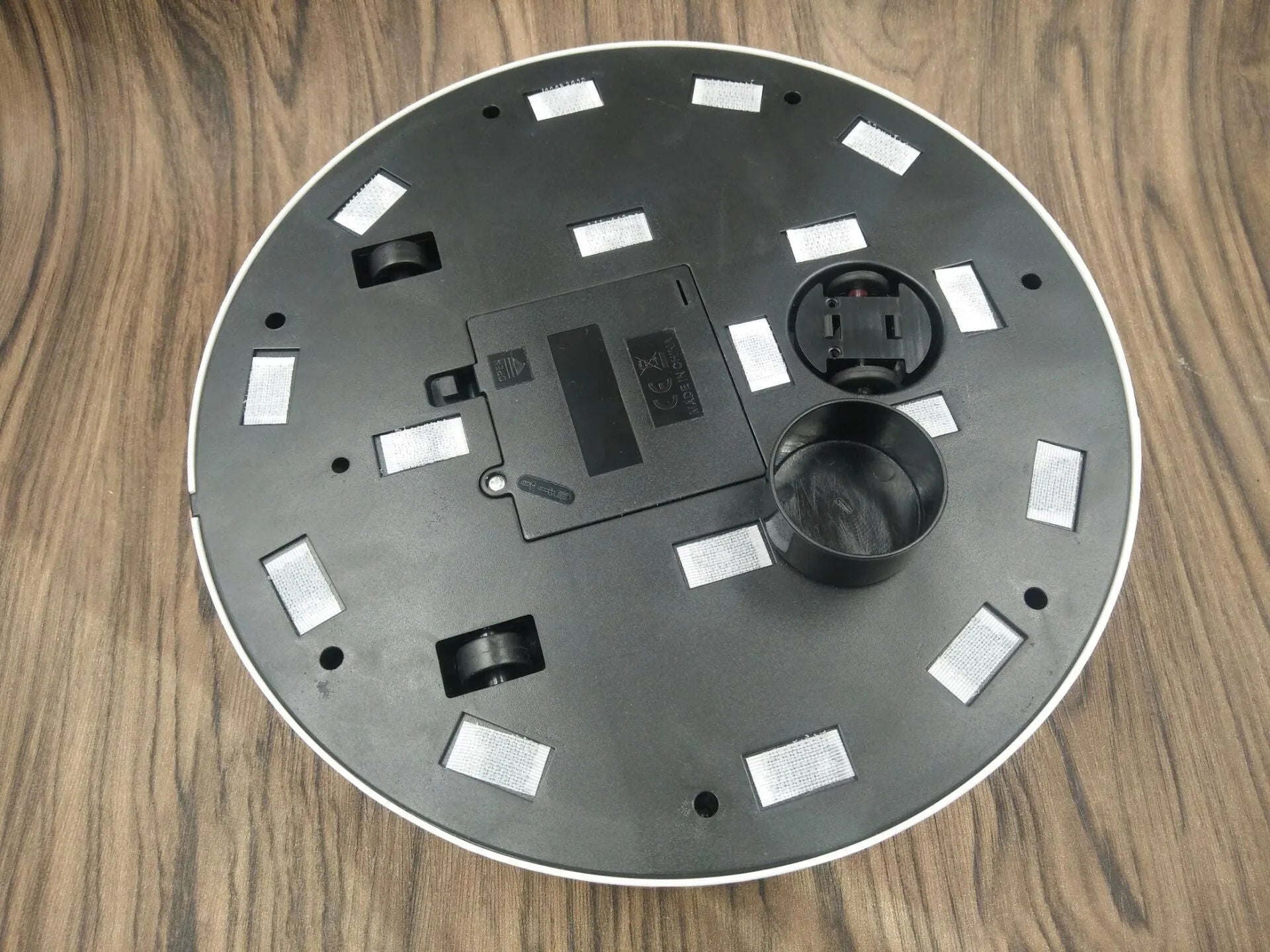 Black or white AC automatic sweeping robot cleaner on a wooden floor