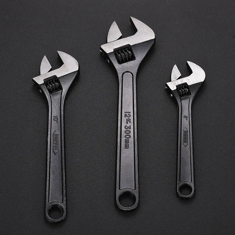 High carbon steel adjustable open-end spanner with black finish on a workbench.