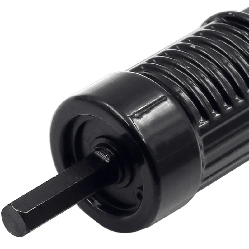 Black metal electric drill rivet gun with adapter and four rivet heads on a workbench.