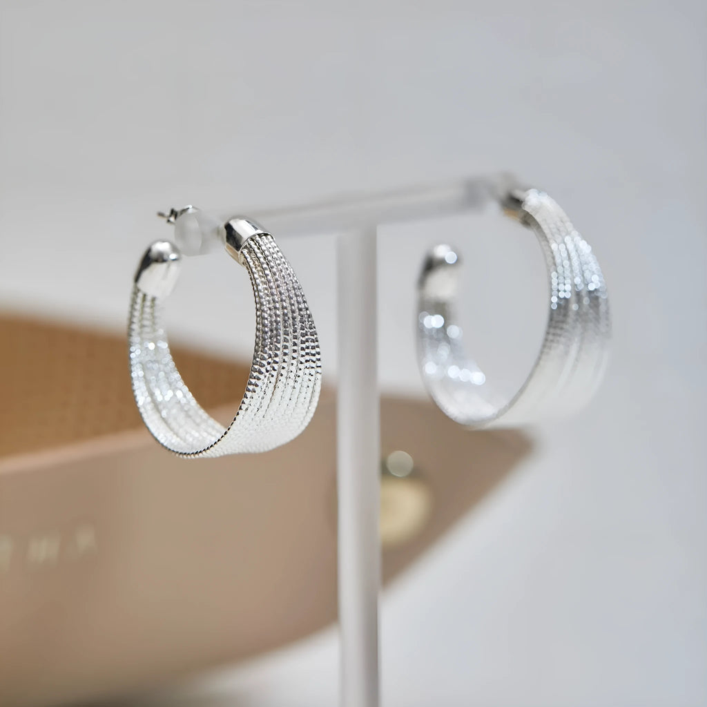 A pair of multi-layer geometric earrings in gold or silver electroplated finish, available as studs or clips.