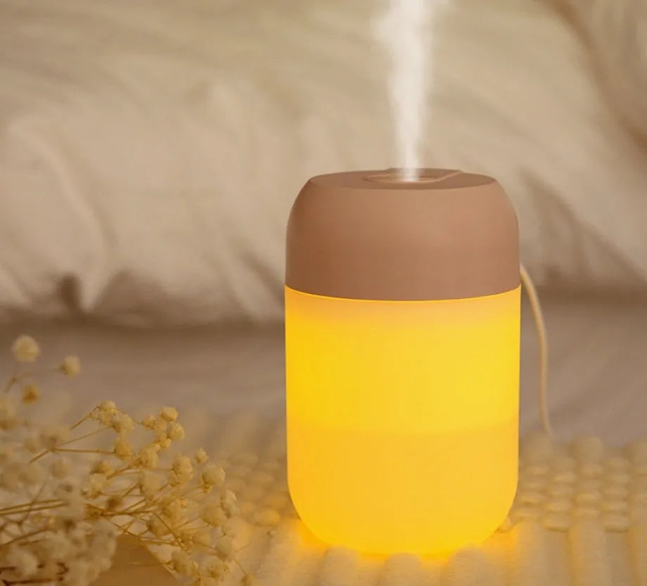 White cylindrical mini USB humidifier with aromatherapy function on a wooden surface.