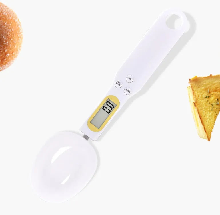 Black electronic measuring spoon scale showing digital display, placed on a kitchen counter.