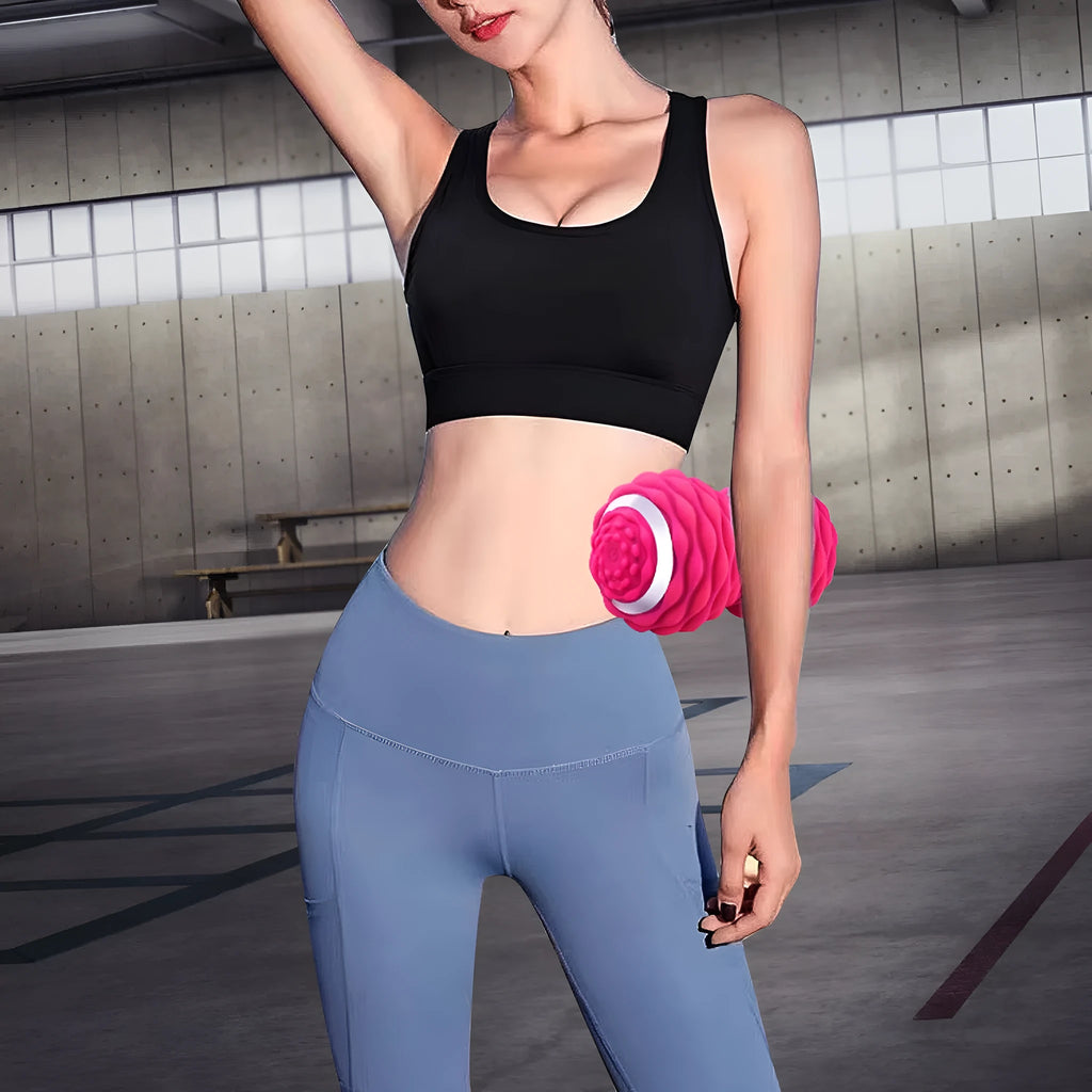 Electric peanut fascia massage ball in black and sky blue on a gym floor for muscle recovery