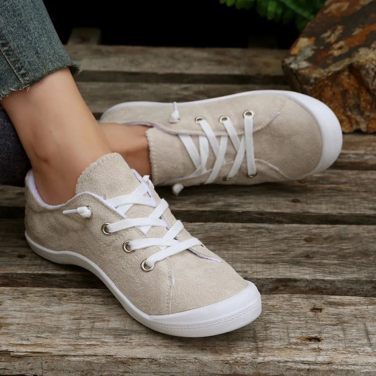 Creamy-white low-top fabric sneaker for women with a rubber sole on a neutral background