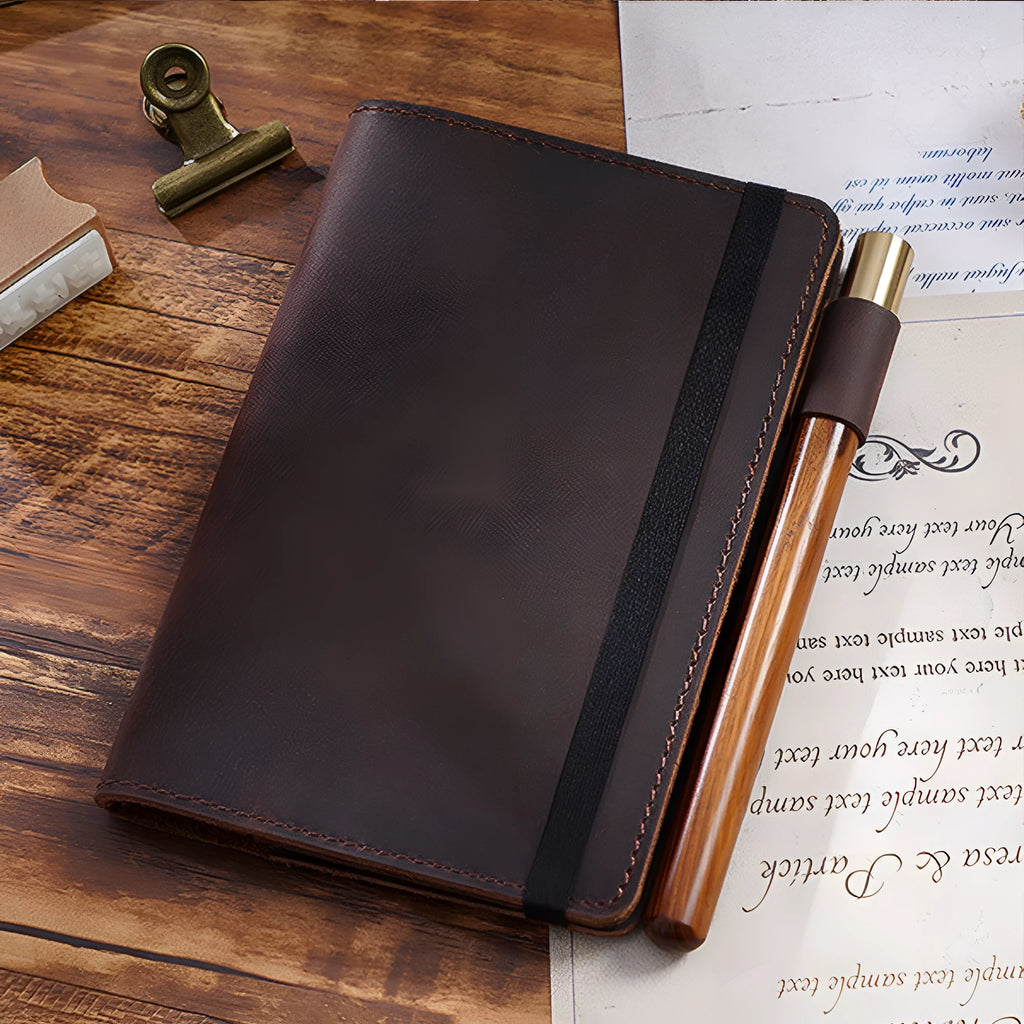 Handmade leather notebook in dark green, open on a desk showing wood-free paper pages.