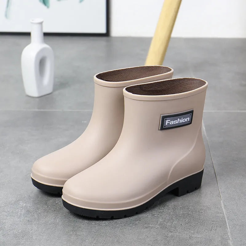 Women's black PVC mid-calf rain boots with a low heel on a wet surface.