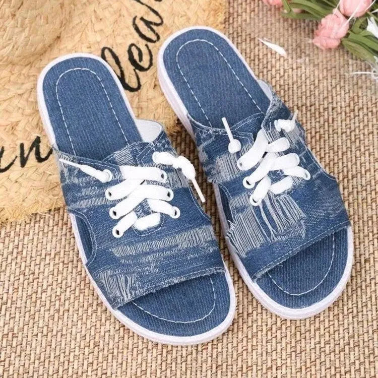 Blue women's Roman-style flat canvas slippers with a rubber sole, shown from the side.