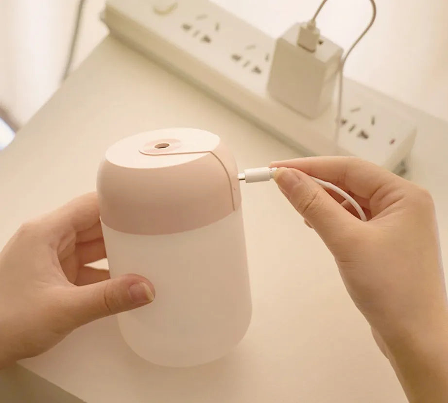 White cylindrical mini USB humidifier with aromatherapy function on a wooden surface.