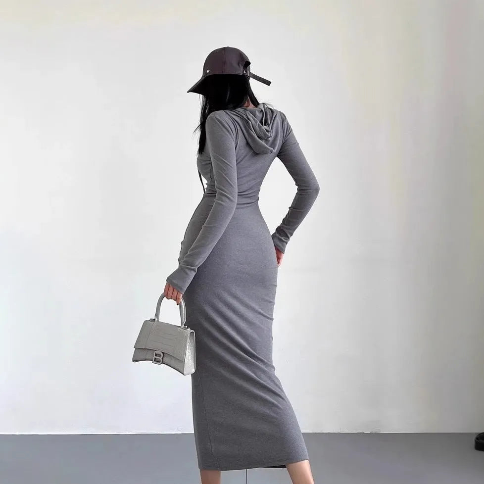 A woman wearing a grey hooded sheath dress with long sleeves and an over-the-knee length.