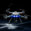 Black quadrocopter drone with four rotors, GPS module, dual cameras, and a 6-channel handheld remote controller.