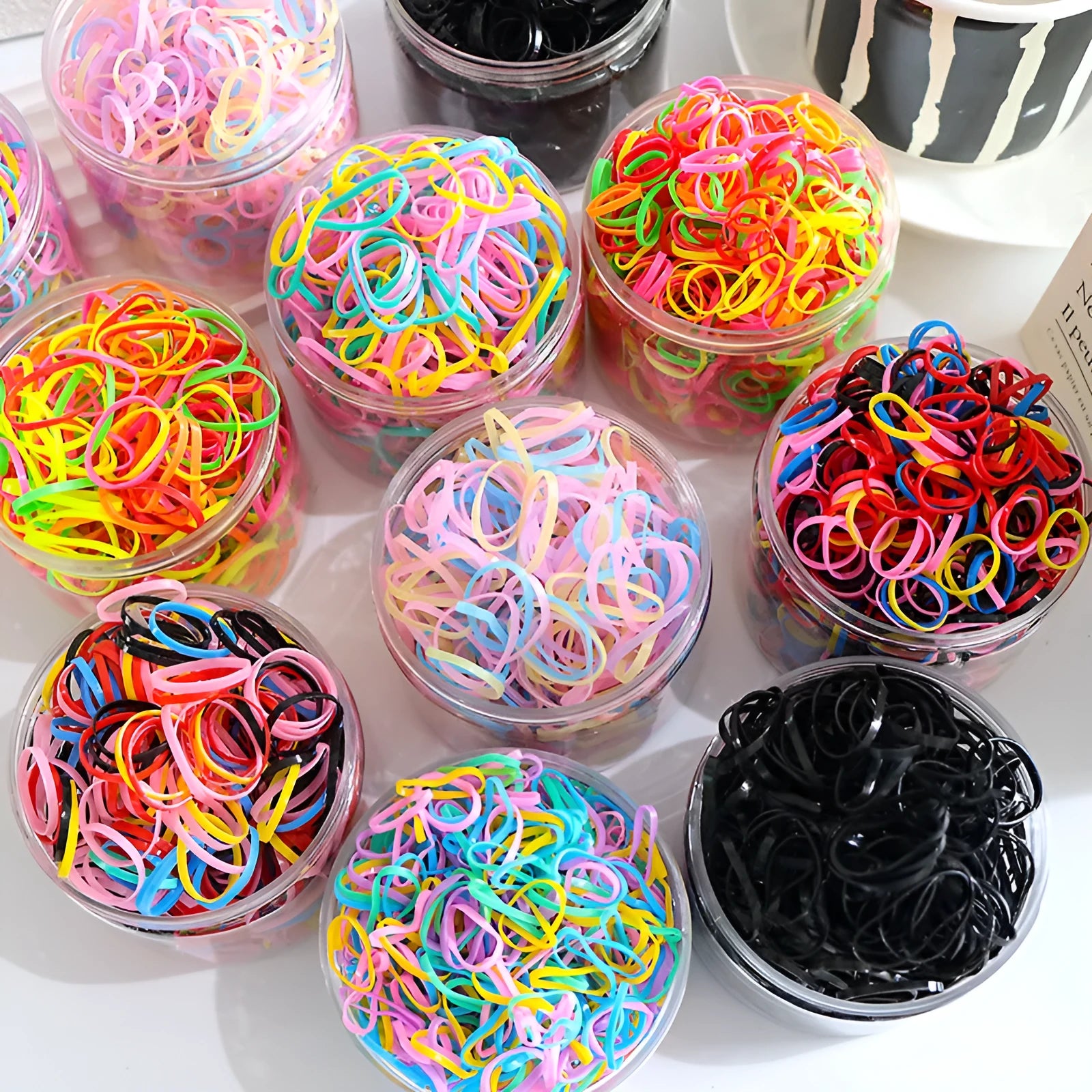 Pack of multicolour TPU baby hair ties for toddlers in a clear reusable container.