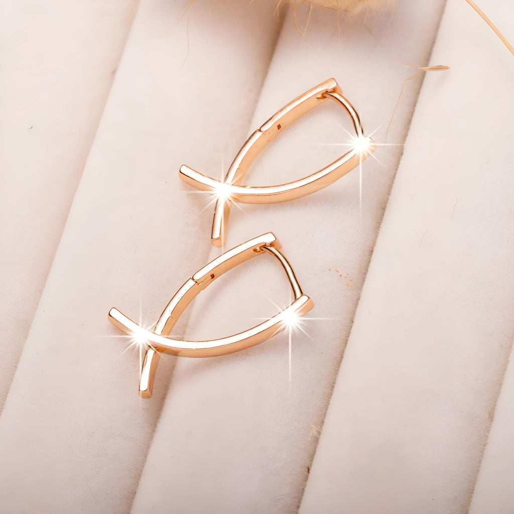 Rose gold coloured cross-shaped earrings on a plain background.