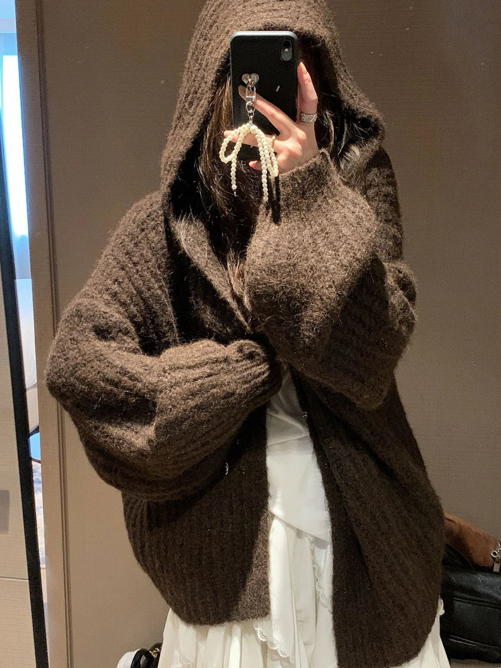 Woman wearing a dark gray retro-style hooded cardigan sweater with a loose fit.