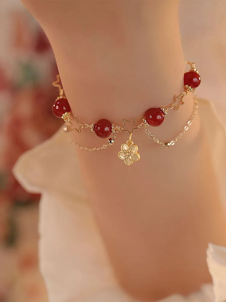 Close-up of a red agate double layer bracelet with floral and peach blossom detailing on a woman's wrist.