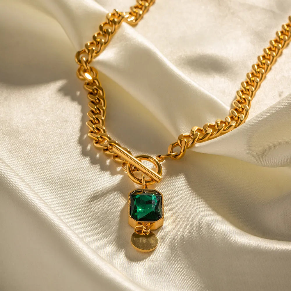Gold electroplated titanium steel necklace with geometric round pendant containing emerald zircon accents