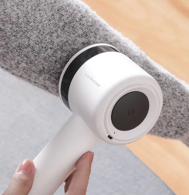 White rechargeable lint remover with three blades, hidden collection container, and ABS build on a plain background