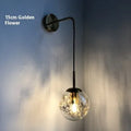 Modern glass wall lamp in golden flower finish mounted beside bed
