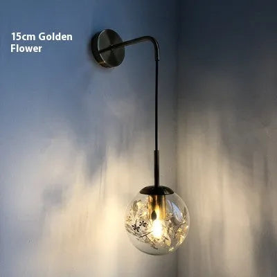 Modern glass wall lamp in golden flower finish mounted beside bed