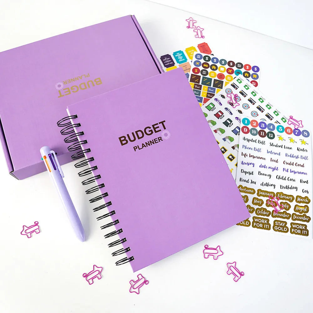 J12 purple coil-bound budget notebook with financial planning stickers and paper clips laid out.