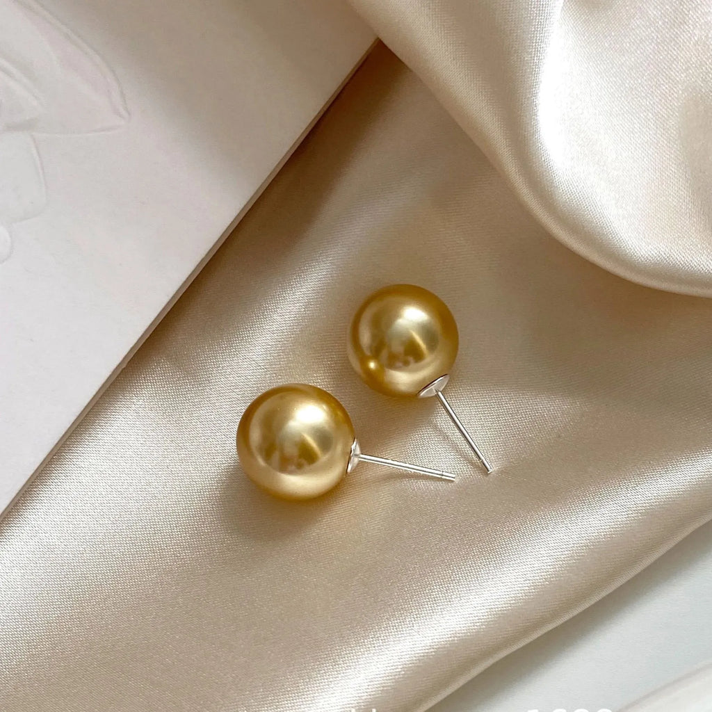 A pair of large pearl stud earrings with an eight-point star geometric setting in silver.