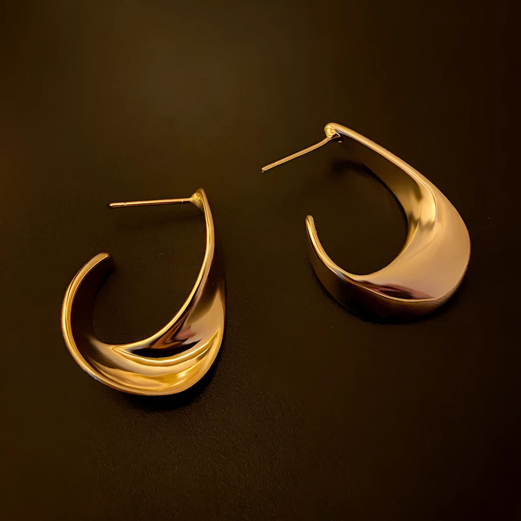 Gold and silver twisted geometric metal earrings with a round design element.