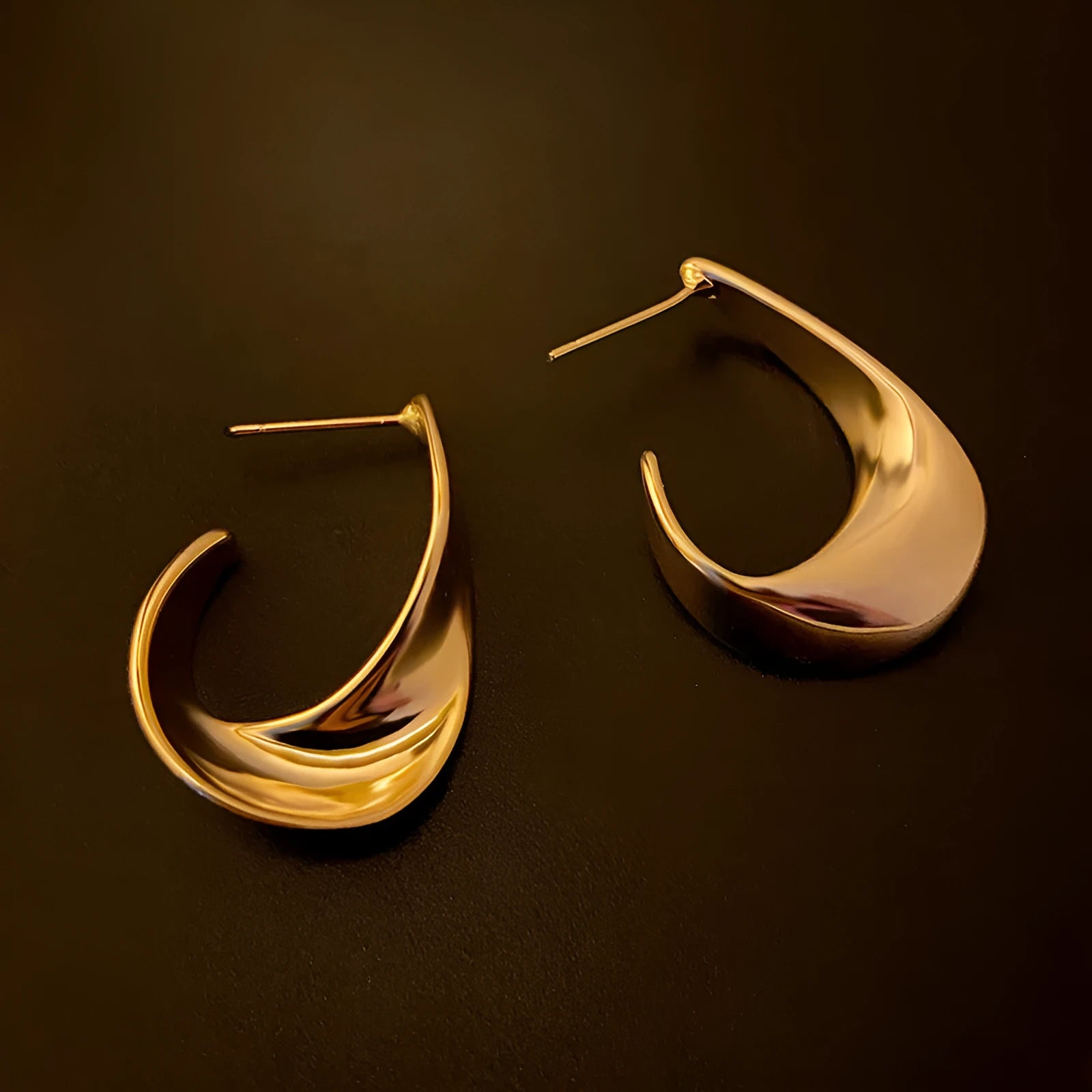 Gold and silver twisted geometric metal earrings with a round design element.