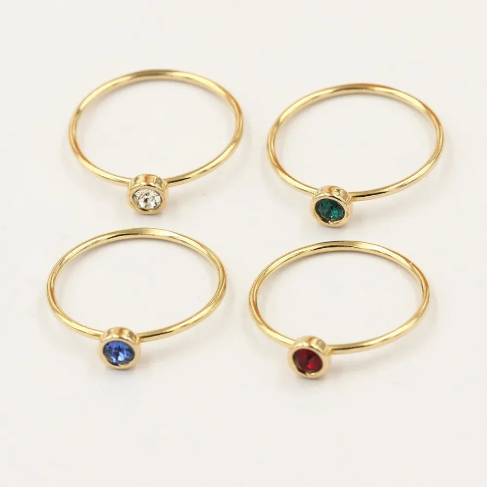 Gilded copper knuckle ring with a blue cubic zirconia stone on a model's hand.