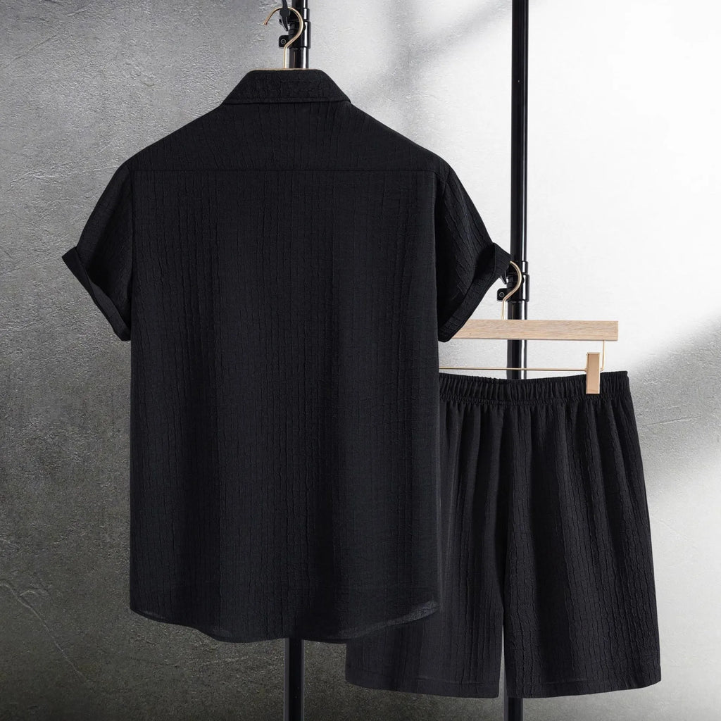Men's black jacquard patterned short sleeve shirt and matching casual shorts laid flat.