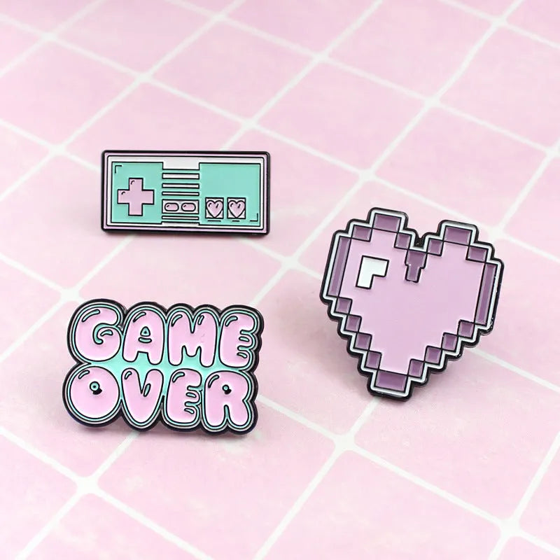 Stereo game console badge pin made from alloy metal on a bag, showing three colour variant options.
