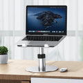 Silver adjustable aluminium laptop stand raised to mid-height with ventilation holes visible.