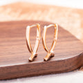 Rose gold coloured cross-shaped earrings on a plain background.