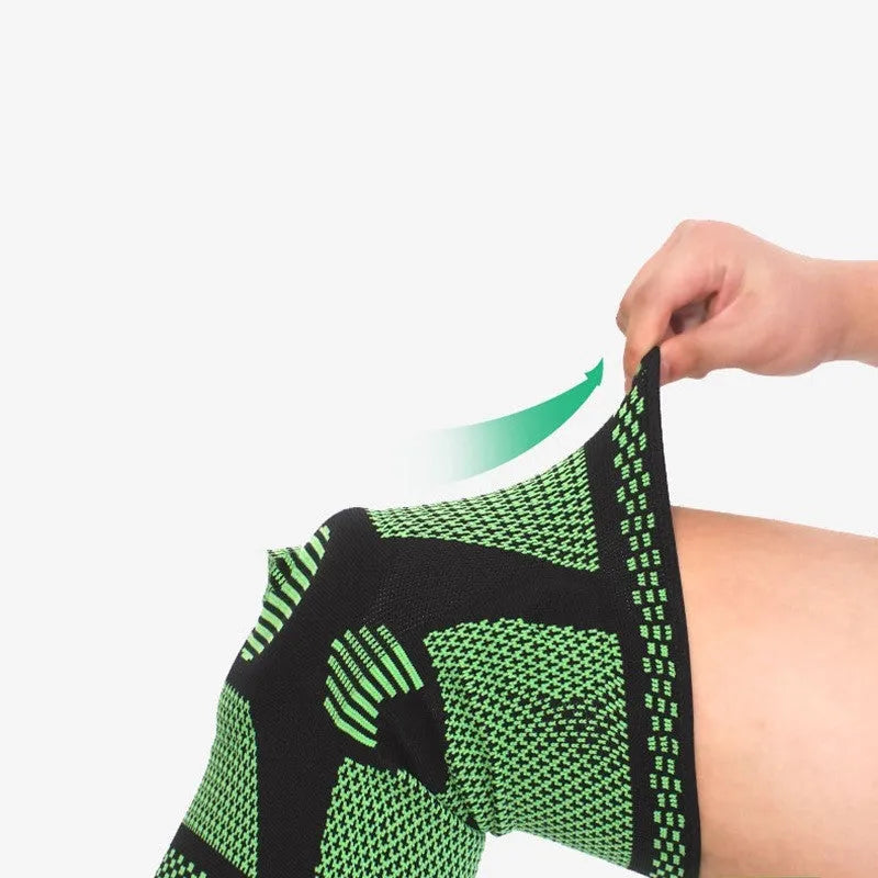 A green polyamide knee pad with a visible silicone spring and adjustable strap, laid flat.