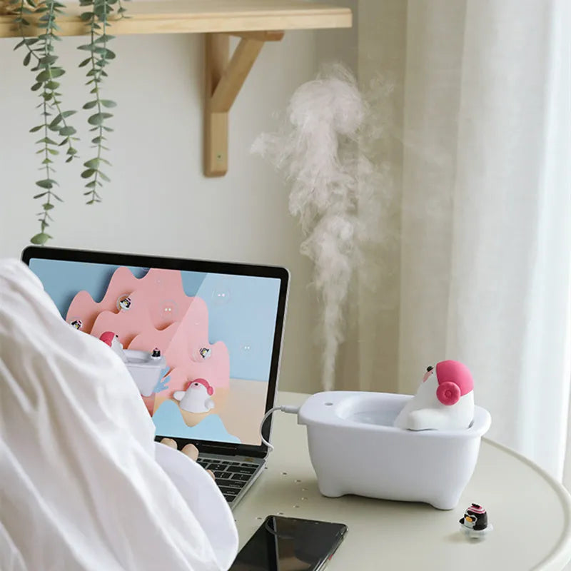 White USB air humidifier with large water tank on a desk next to a laptop.