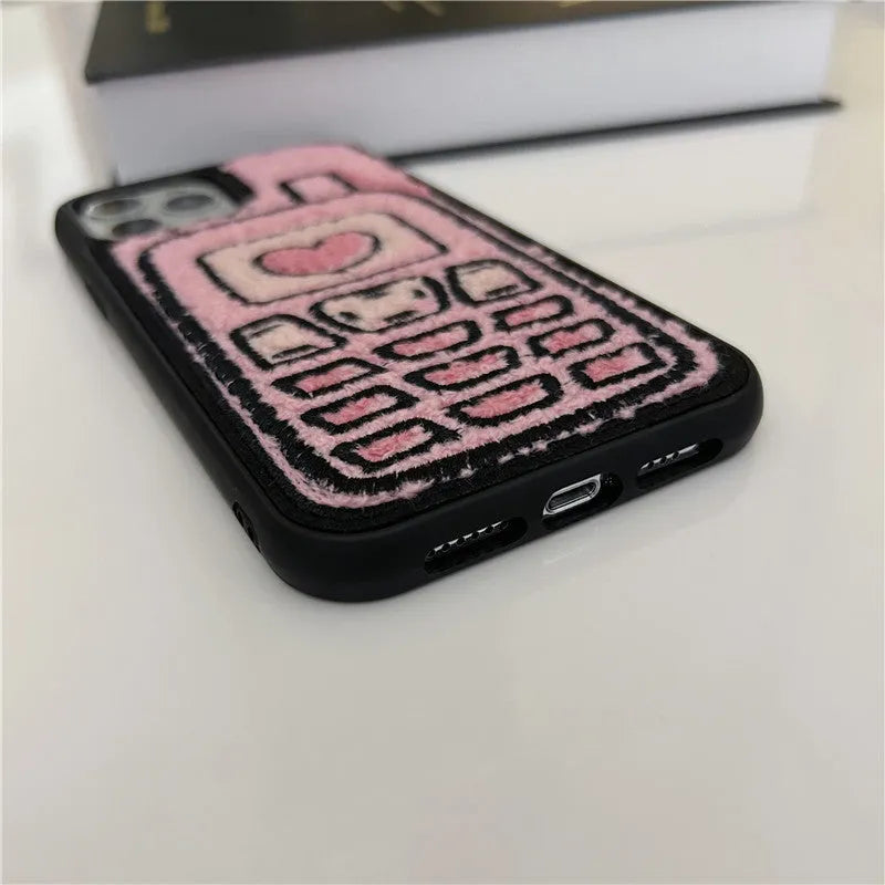 Pink towel embroidered soft TPU back cover case for iPhone models on a table.