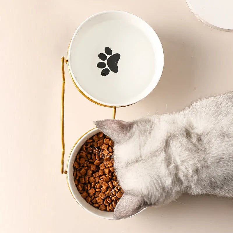 White ceramic cat bowl with cat paw print in a black iron frame stand with cat ears.