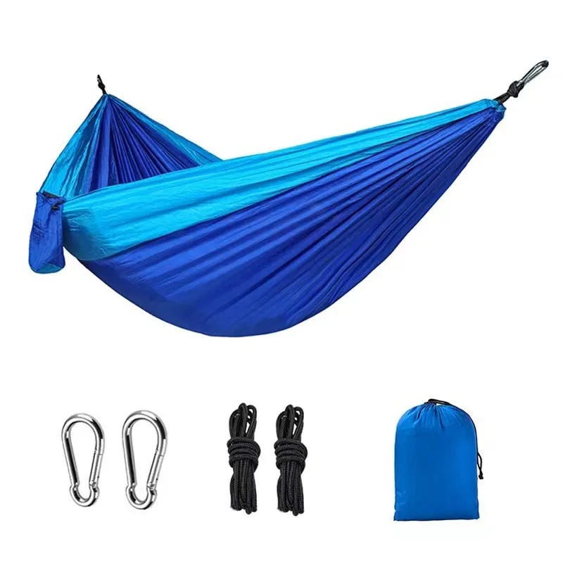 Large blue outdoor hammock made from parachute nylon fabric hanging between trees