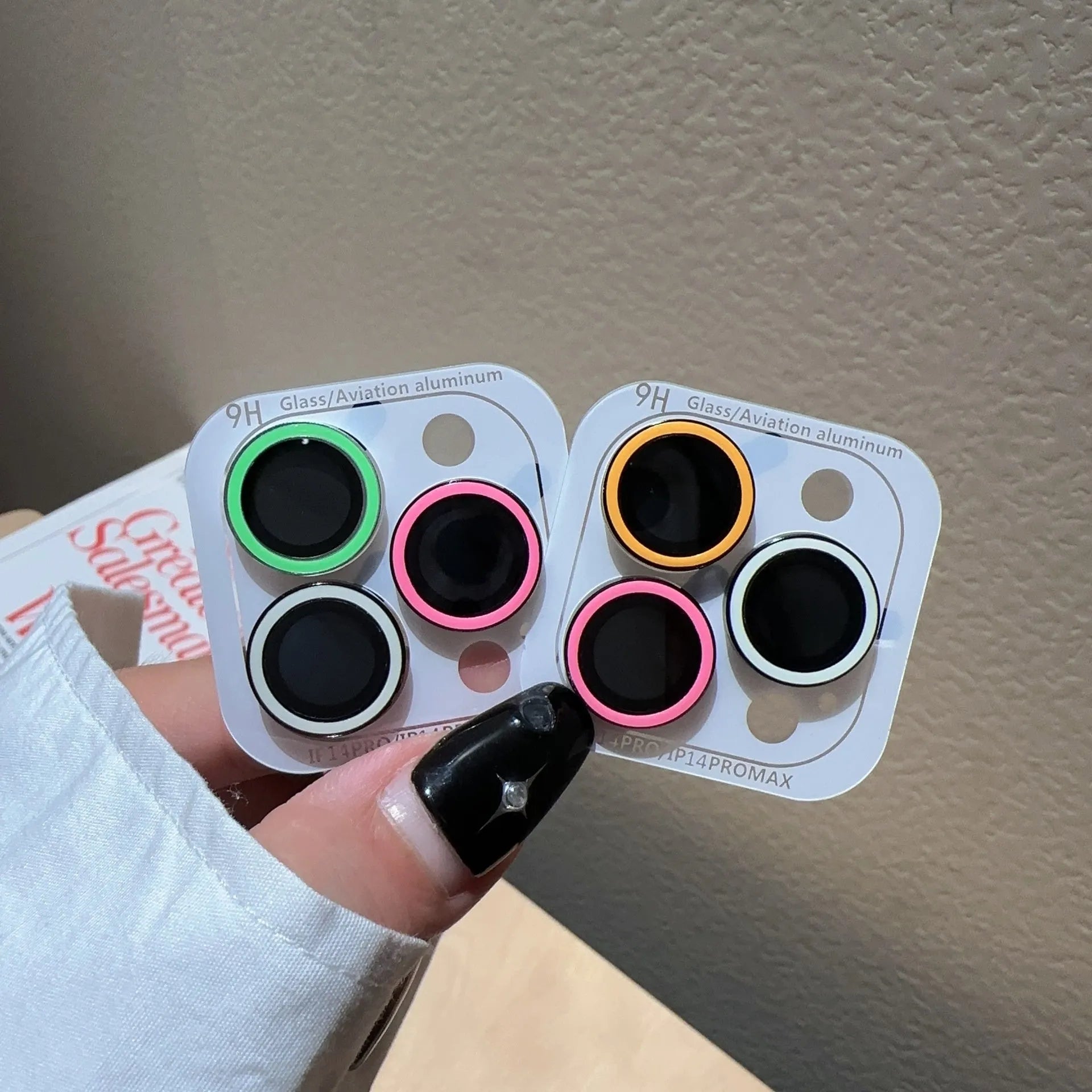 Luminous tempered glass camera lens protector for iPhone 14 Pro Max showing three-hole cutout in yellow blue pink