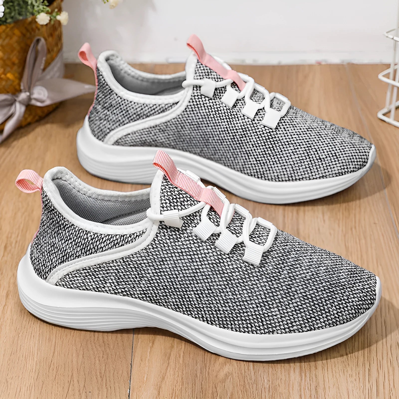 Women's low-top black casual sneakers with mesh upper and lace-up front on a grey background.