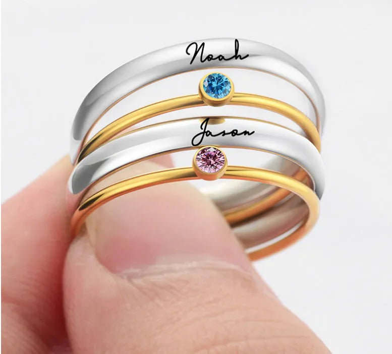 December birthstone geometric engraved ring in titanium steel with gold-coloured handle on a grey background.