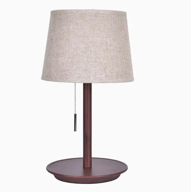 Walnut-coloured solid wood desk lamp with a white fabric shade on a wooden table.