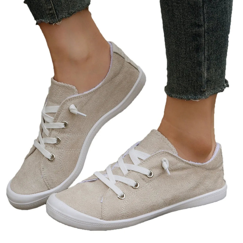 Creamy-white low-top fabric sneaker for women with a rubber sole on a neutral background