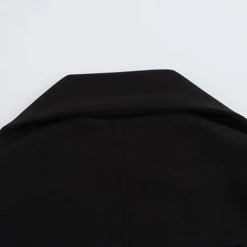 Women's long black polyester blend overcoat with a detachable artificial fur collar, showing pocket detail and street-fashion fit.