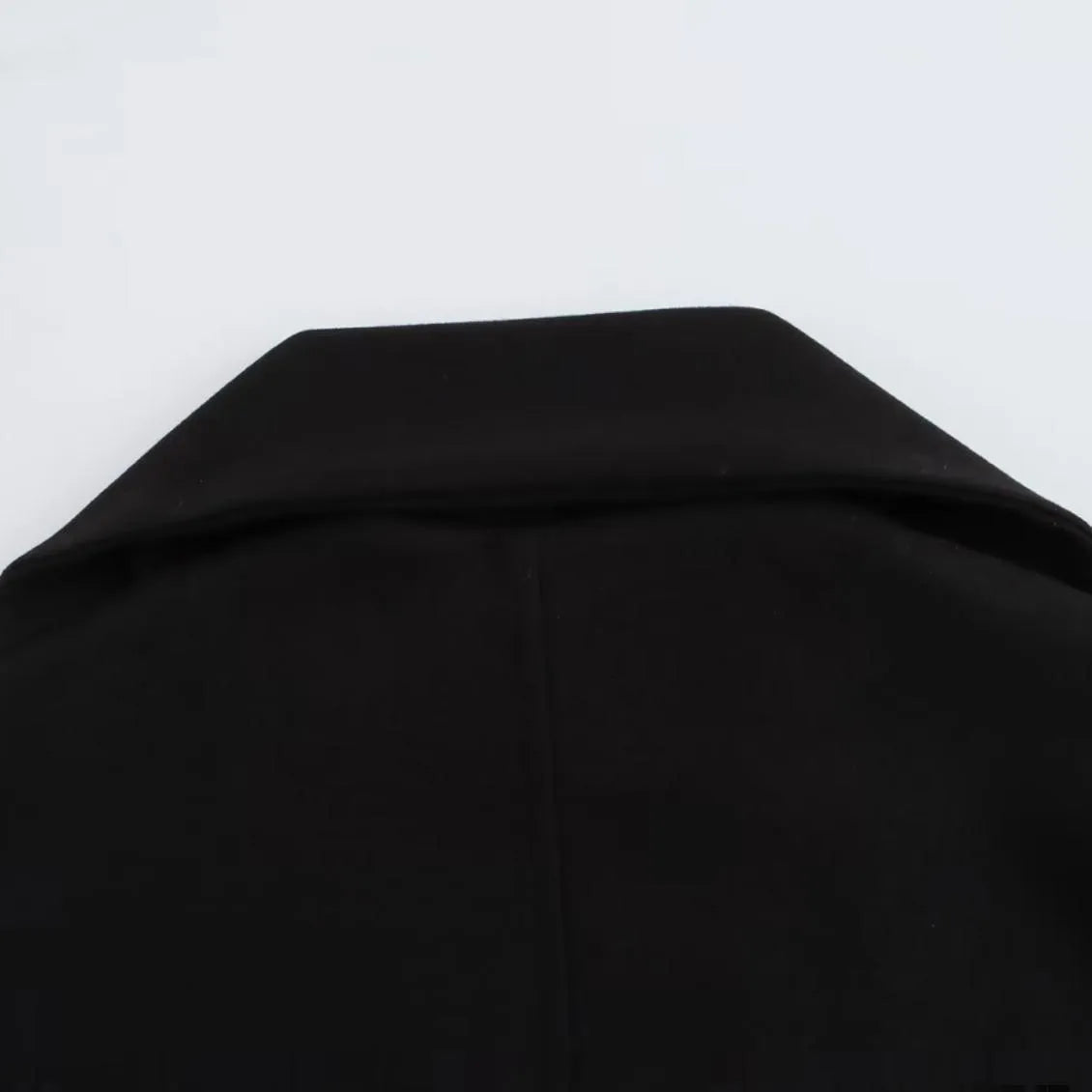 Women's long black polyester blend overcoat with a detachable artificial fur collar, showing pocket detail and street-fashion fit.