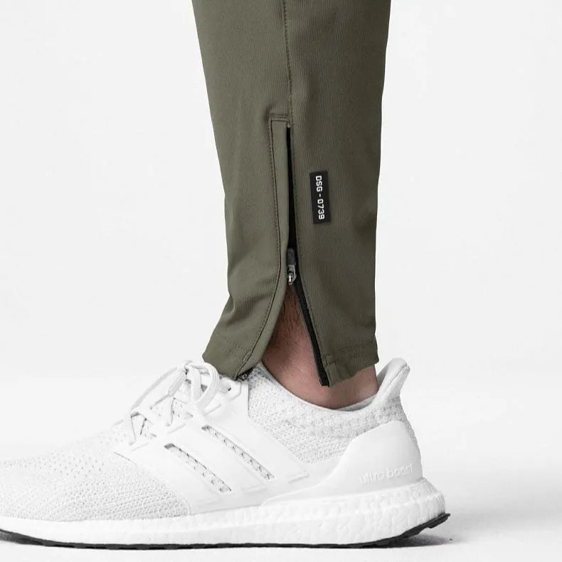 Man wearing dark grey loose-fit ankle-tied running pants made from quick-drying polyester fabric.