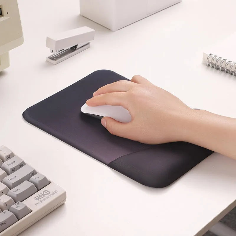 Square blue cloth silicone wrist rest mouse pad on a desk.