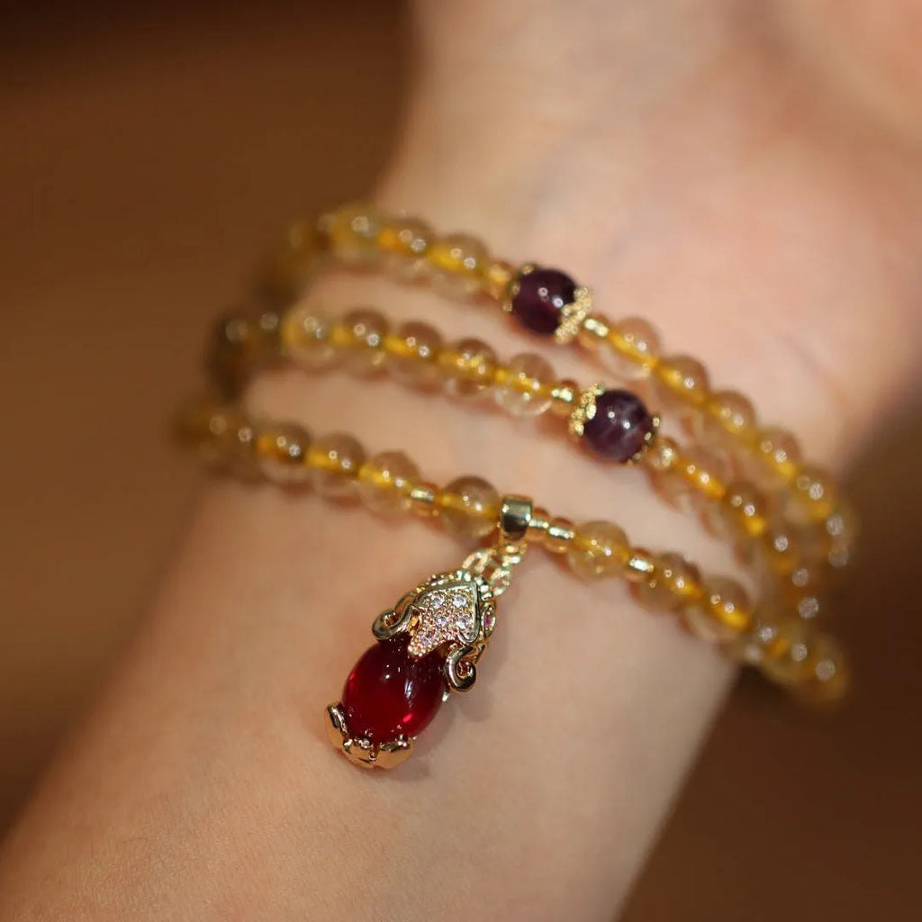 Natural gold rutilated quartz bracelet with three gold rings on wrist