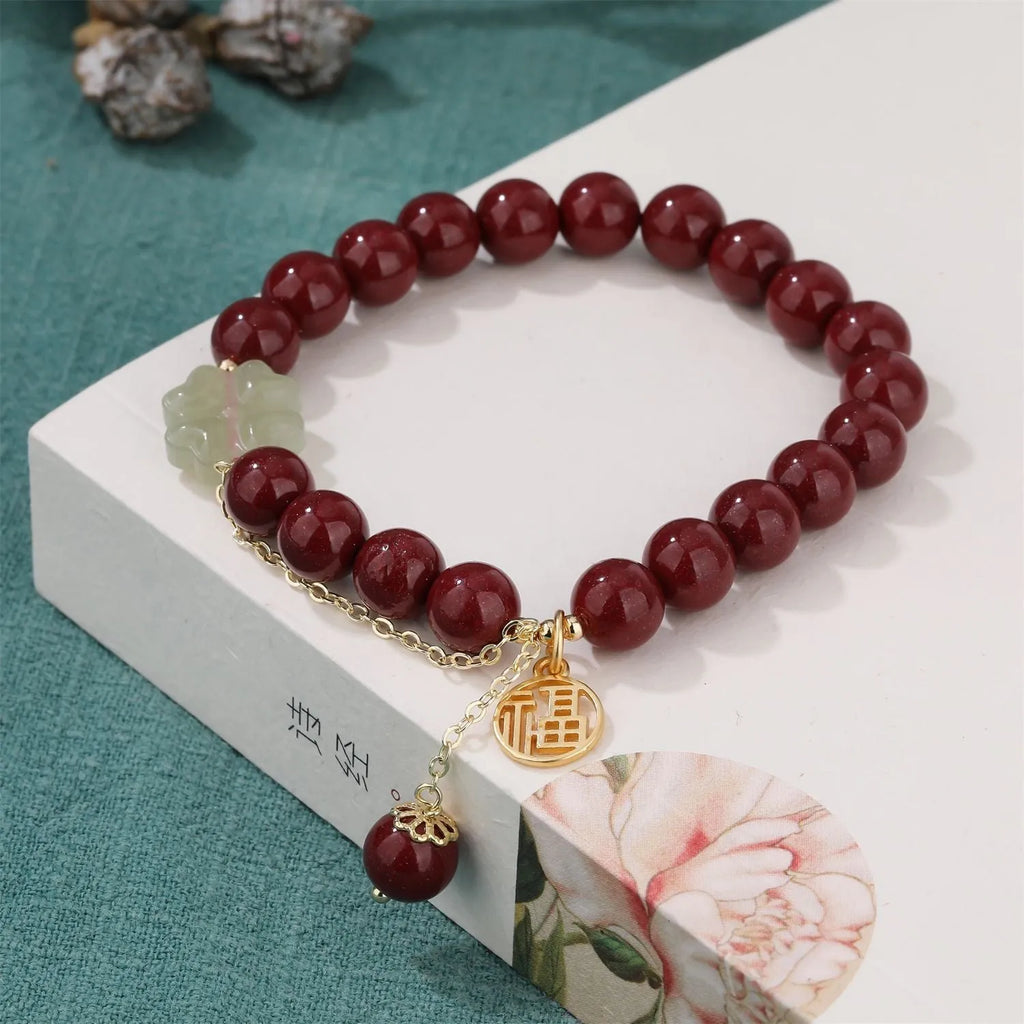 Close-up of a purple gold sand cinnabar bracelet with a fu character charm and adjustable tassel.