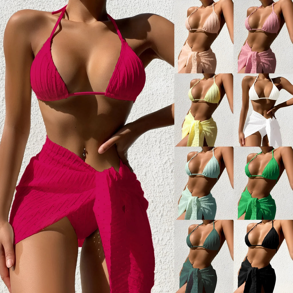 Women's black halterneck backless bikini top and bottom with a matching sheer mesh skirt laid flat.