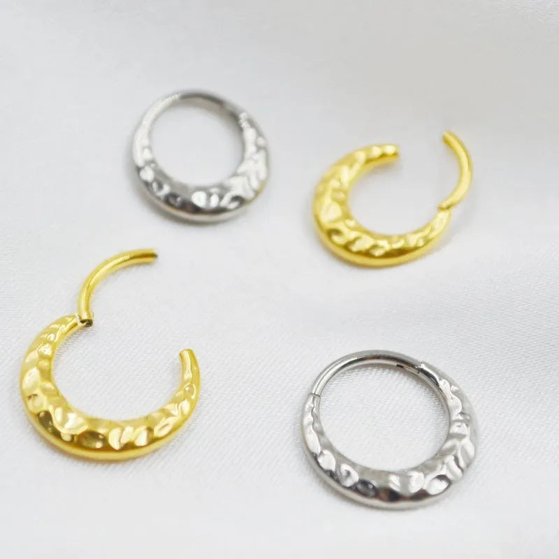 Close-up of a titanium alloy concave-convex nose ring in gold finish, showing detailed carving texture.