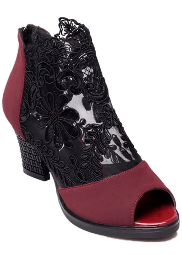 Black lace gladiator sandals with a square high heel and zip closure on a woman's foot.
